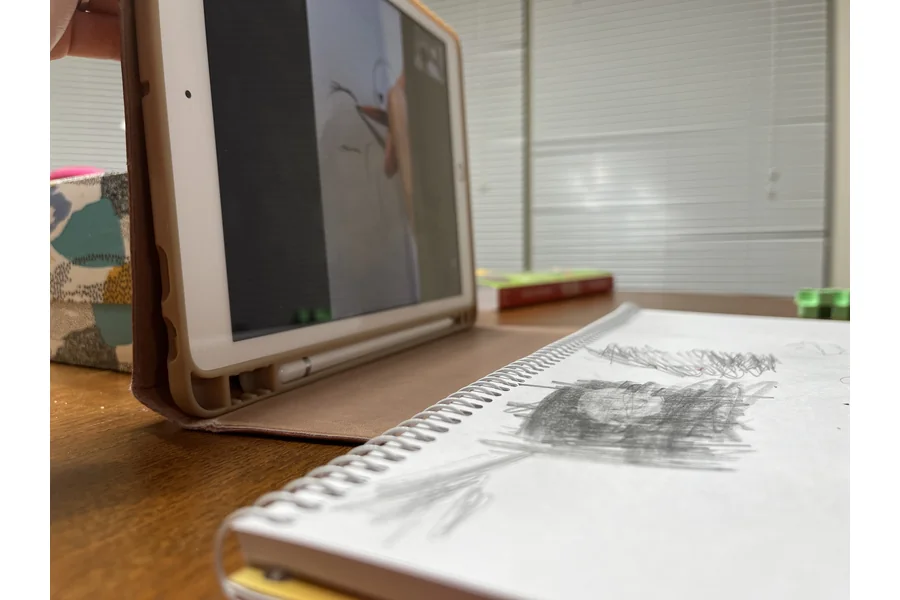 まなぶてらすの絵のレッスン中。iPadに先生の手元を映しながら、手前のスケッチブックに鉛筆で描いている
