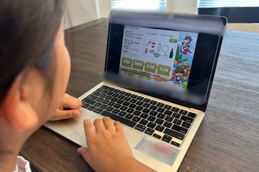 MacBookですららの社会のレクチャーを受ける小学4年生の後ろ姿。画面にはゴミの分別が映っている