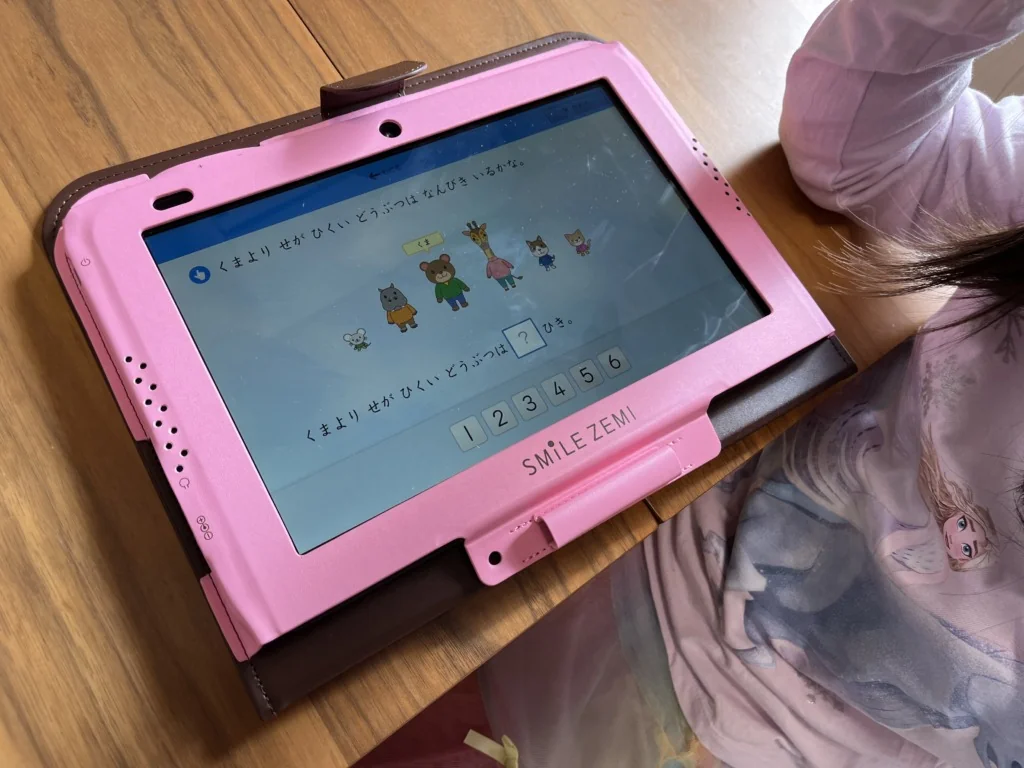 ピンクのケースに入ったスマイルゼミのタブレット。「くまよりせがひくいどうぶつはなんびきいるかな」という数の問題が表示されている