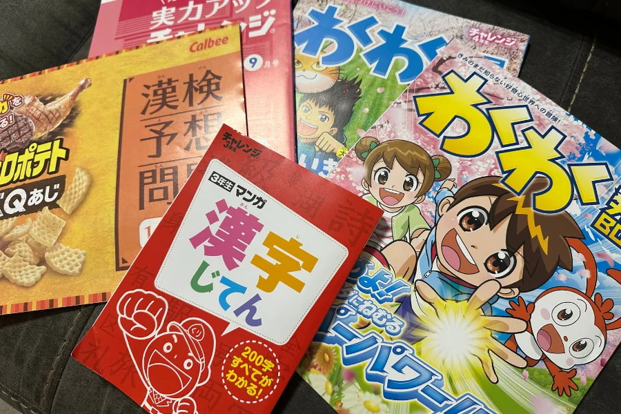 進研ゼミの紙教材の付属物を広げた写真。実力アップチャレンジ9月号、漢字検定の予想問題集、3年生の「マンガ漢字じてん」、情報誌「わくわく」2冊が重なっている